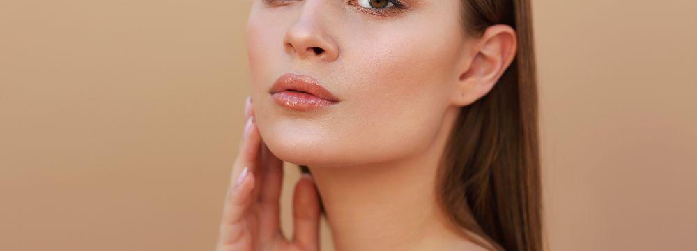 Youthful woman touching jawline with hand while looking at camera